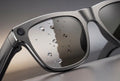 Close-up of a pair of smart AI glasses with water droplets on the lens.